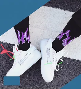 Close-up of black mid-calf socks with purple flame patterns on street pavement