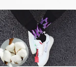Close-up of black cotton socks with purple flame pattern worn with white sneakers