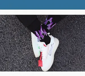 Close-up of black cotton socks with vibrant purple and white flame patterns on asphalt.