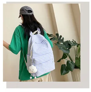 Back view of a girl wearing a blue and white checkered backpack with a cute cloud charm