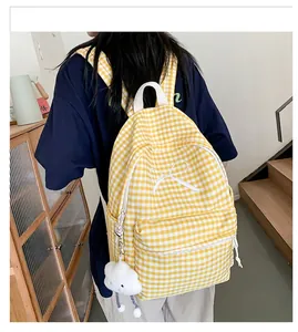 Detailed view of yellow checkered backpack with white bow and cute cloud charm pendant