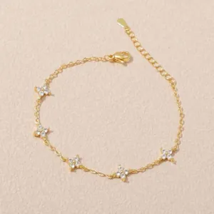 Dettaglio elegante bracciale a quadrifoglio dorato con pietre in zirconia bianca