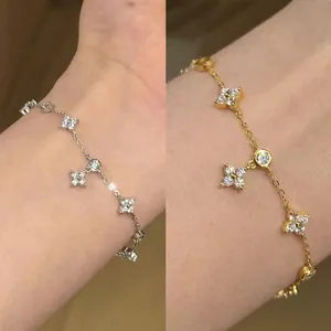 Primo piano di eleganti braccialetti a quadrifoglio minimalisti in oro e argento al polso.
