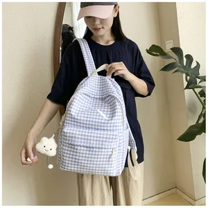 Girl wearing a light blue checkered backpack with a bow detail and a soft cloud charm