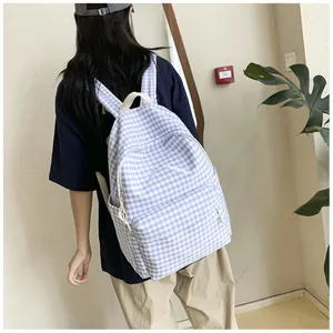Lifestyle detail view of a light blue gingham backpack with a white bow embroidery.