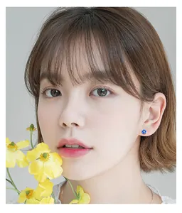 Close-up view of a delicate blue flower S925 silver stud earring worn by an Asian model
