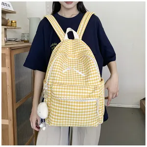 Model wearing a yellow and white gingham backpack with a cute bow detail and plush charm.