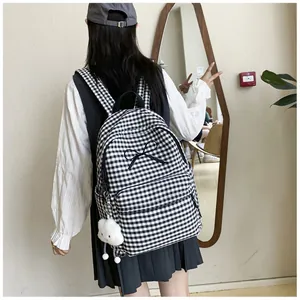 Back view of a stylish girl carrying a black and white checkered backpack with a cute bow detail