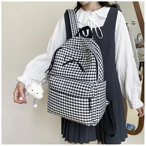 A detailed view of a black and white gingham backpack featuring a bow and cloud charm