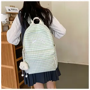 Back view of a green checkered school backpack with white bow embroidery on a model