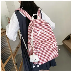 Back view of red checkered school backpack with white bow and cute cloud keychain