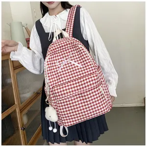 Lifestyle detail of a red and white gingham school backpack with white bow embroidery