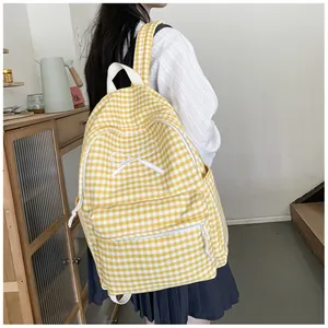 Yellow checkered student backpack with a white bow detail, worn by a model indoors.