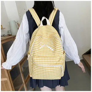 Detail of yellow and white gingham backpack featuring a white embroidered bow design.