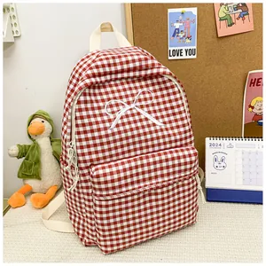 Red and white checkered school backpack with white bow detail in a cozy study setting
