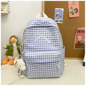 Detailed view of the blue plaid student backpack with white bow embroidery and cloud charm.