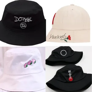 Detail view of four different embroidered cotton bucket hats in black, beige and white.