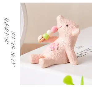 Macro view of a cute pink resin pig figurine holding colorful dango for home decor