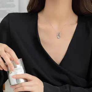 Minimalist silver oval hollow pendant necklace worn by woman in black V-neck top
