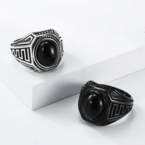 Close-up van twee vintage titaniumstalen ringen met zwarte ovale stenen en inkepingen.