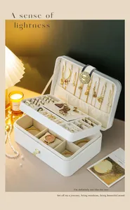 Open multi-layer white jewelry storage box showcasing organized rings and gold necklaces