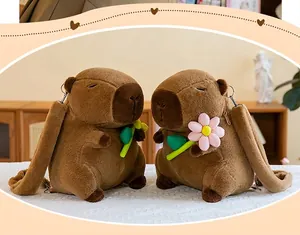 Detail view of two cute brown capybara plush backpacks with flower and leaf accessories