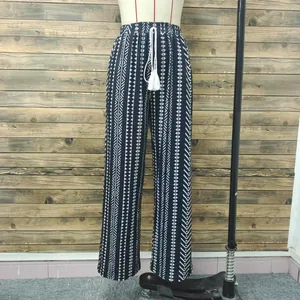 Dettaglio dei pantaloni dritti da donna con stampa geometrica bianca e nera e nappa