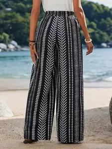 Dettaglio dei pantaloni larghi da donna con stampa geometrica su sfondo di spiaggia