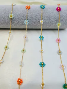 Detailed macro view of colorful handmade woven flower charms on a gold-plated jewelry chain.