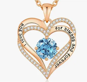 Detailed macro view of rose gold heart necklace pendant with 'I love you' engraving and blue gem.
