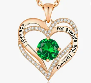 Detailed view of rose gold double heart necklace with green stone and engraving