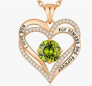 Detail of a rose gold double heart necklace with a green gemstone and romantic engraving.