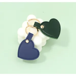 Detailed macro view of heart-shaped leather keychains in navy and forest green