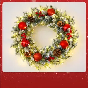 Detailed view of a Christmas wreath with red ornaments, pine cones and warm LED lights