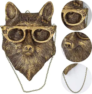 Close-up detail of antique bronze animal wall decor with vintage gold glasses and hanging chain.