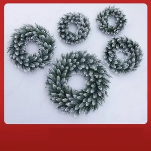 Detailed view of five flocked green Christmas wreaths in various sizes on white surface
