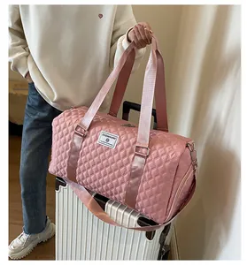 Pink quilted large capacity travel duffel bag on white suitcase for short trips