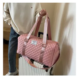 Detail view of pink quilted travel bag with ZUOMANNI logo on white suitcase
