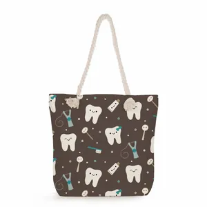 Detail of a brown canvas tote bag featuring a cute cartoon dental pattern and rope handle