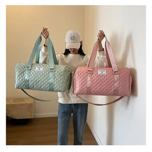 Detail view of the lightweight quilted travel duffel bags in pink and mint green.