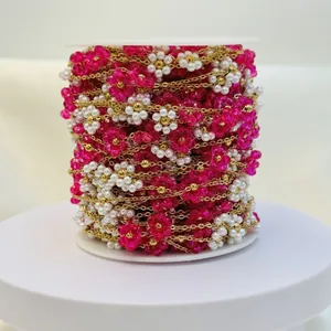 Macro view of handmade pink and white woven flower chain on spool for DIY jewelry