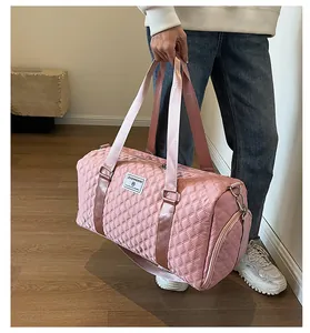 Close-up of large pink quilted duffle bag carried by hand in a lifestyle setting.
