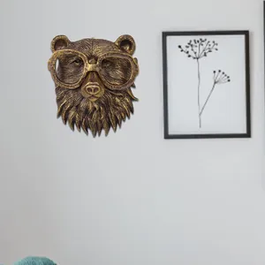 Detailed view of vintage faux bronze bear head wall hanging with glasses on grey wall