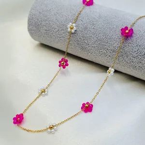 Close-up of handmade pink and white woven flower necklace with gold-plated chain.