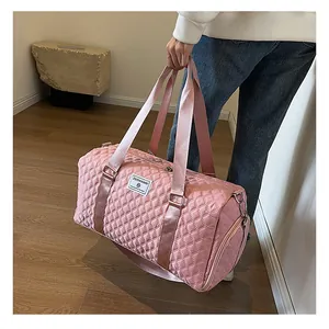 Detailed view of pink quilted travel bag held by a person in a minimalist interior