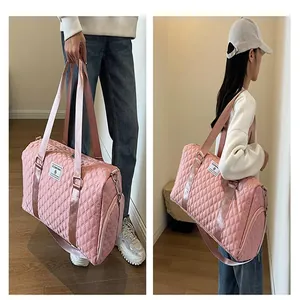 Pink quilted large capacity travel duffel bag shown carried by a model in a lifestyle setting