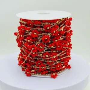 Close-up of vibrant red handmade flower beaded chain wrapped on a white spool for DIY