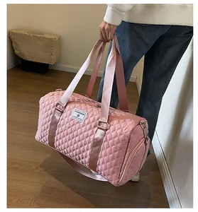 Detail view showing a pink quilted large capacity travel duffel bag held by a person
