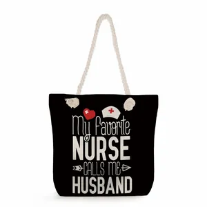 Close-up detail of nurse themed black tote bag with white slogan and rope handles