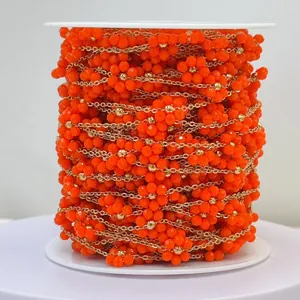 Detailed macro view of orange beaded flower chain for DIY jewelry making on a spool